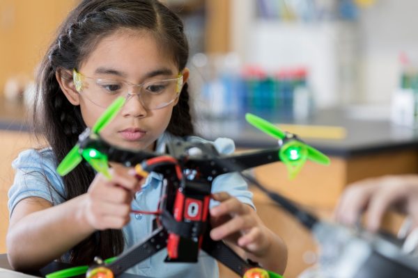 Focused schoolgirl builds quadcopter Smart STEM schoolgirl concentrates as she finishes building a drone during robotics class.